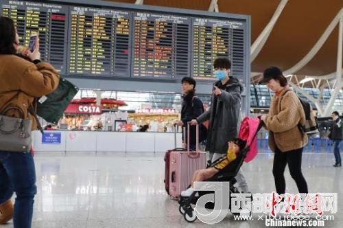 旅客帶著孩子前往辦票柜臺(tái)辦理登機(jī)手續(xù)?！∫罅⑶?攝
