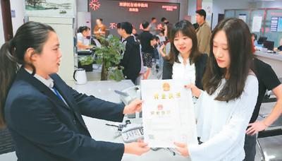 河北省承德市網(wǎng)絡(luò)代購經(jīng)營者陳晨(右)從工作人員手中接過帶有統(tǒng)一社會(huì)信用代碼的營業(yè)執(zhí)照。 劉環(huán)宇攝(人民圖片)