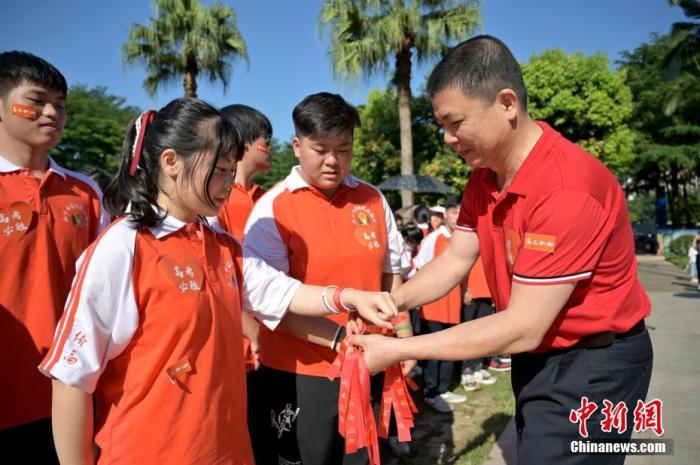 資料圖：廣西華僑實(shí)驗(yàn)高中的教師為高三學(xué)子系上紅絲帶，盼望學(xué)子高考必勝。 俞靖 攝